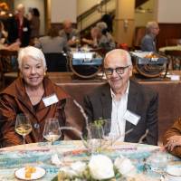 Four event guests sitting at table and smiling for camera